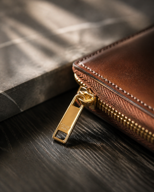 Gold zipper pull on a brown leather bag