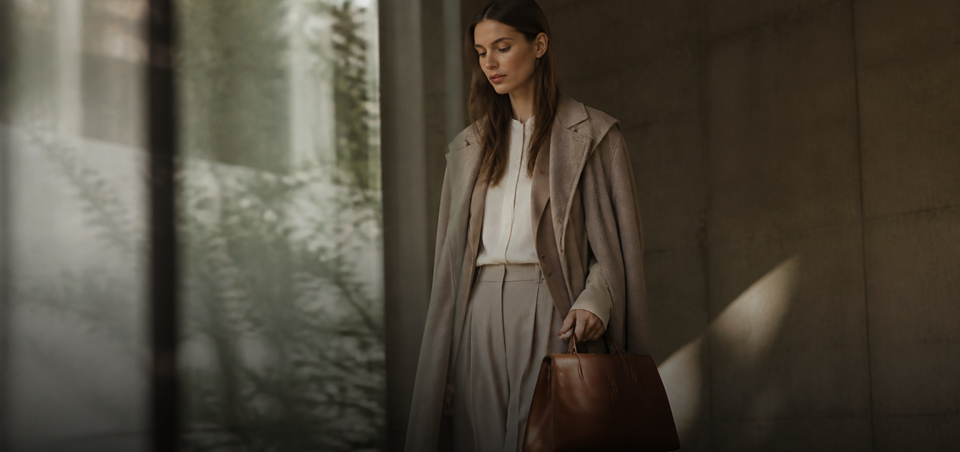 Woman in a taupe suit holding a brown Pakito bag