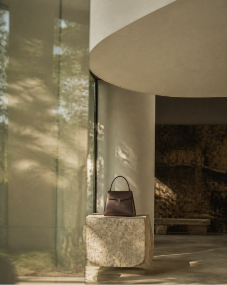 Brown Pakito handbag displayed on a stone plinth in a concept store