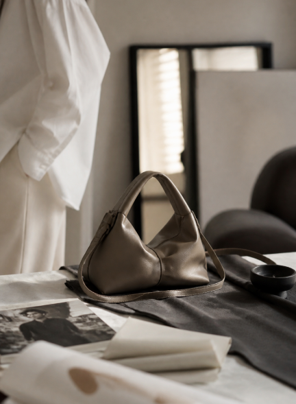 Pakito handbag arranged on a studio table beside fabric and photographs