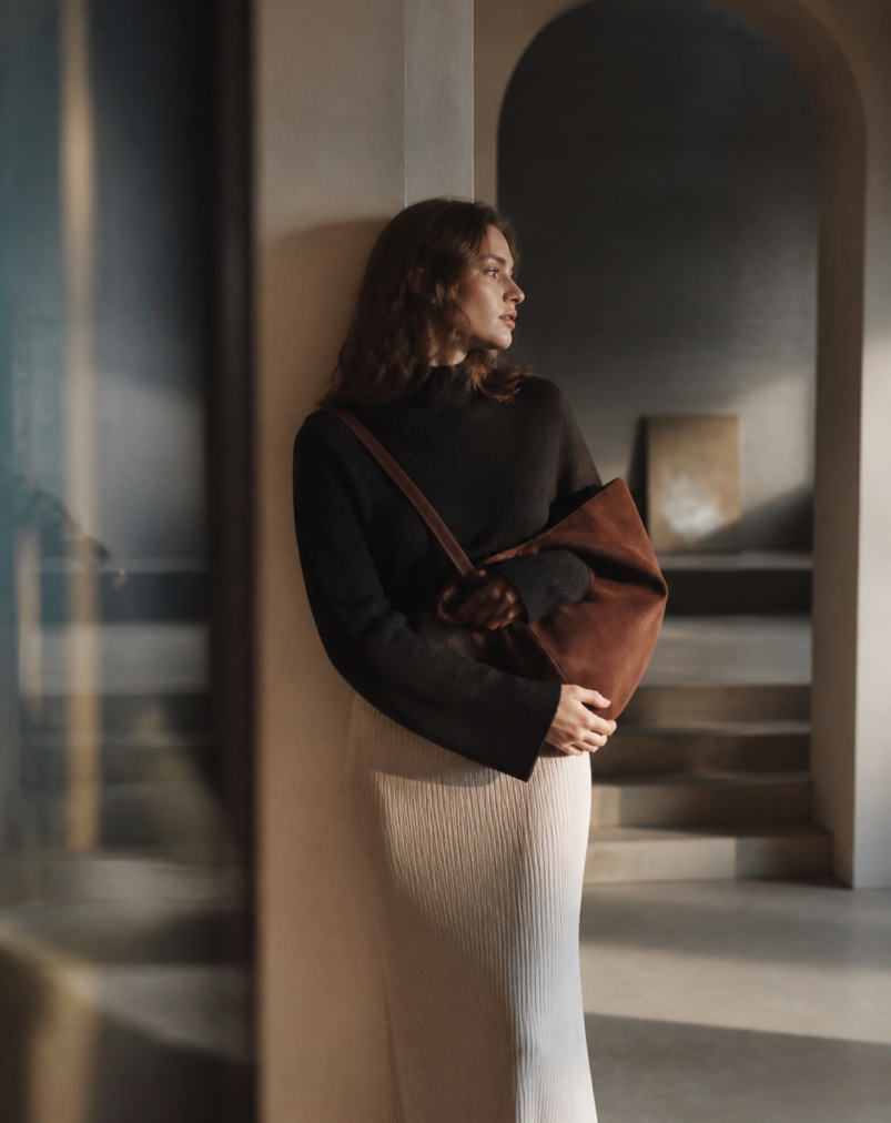 Woman carrying a brown Pakito handbag in a softly lit interior
