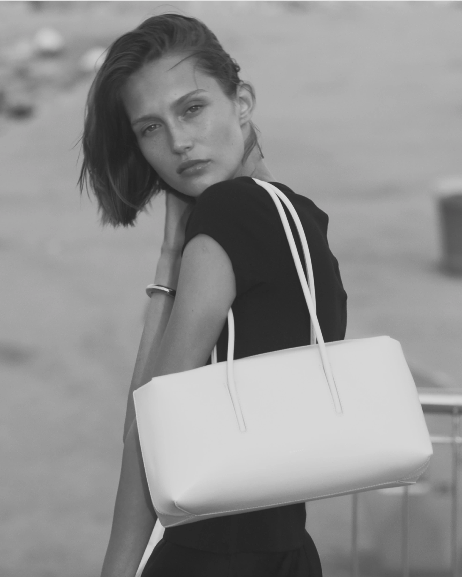 Black-and-white portrait of a woman carrying a white handbag