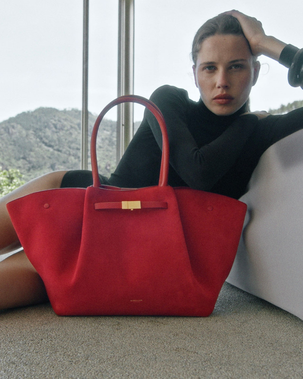 Woman seated beside a red handbag