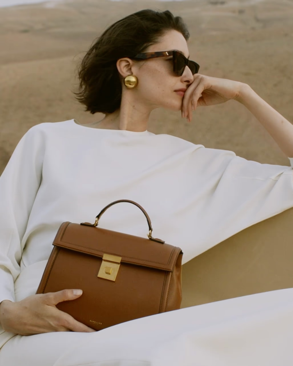Woman in sunglasses holding a brown handbag