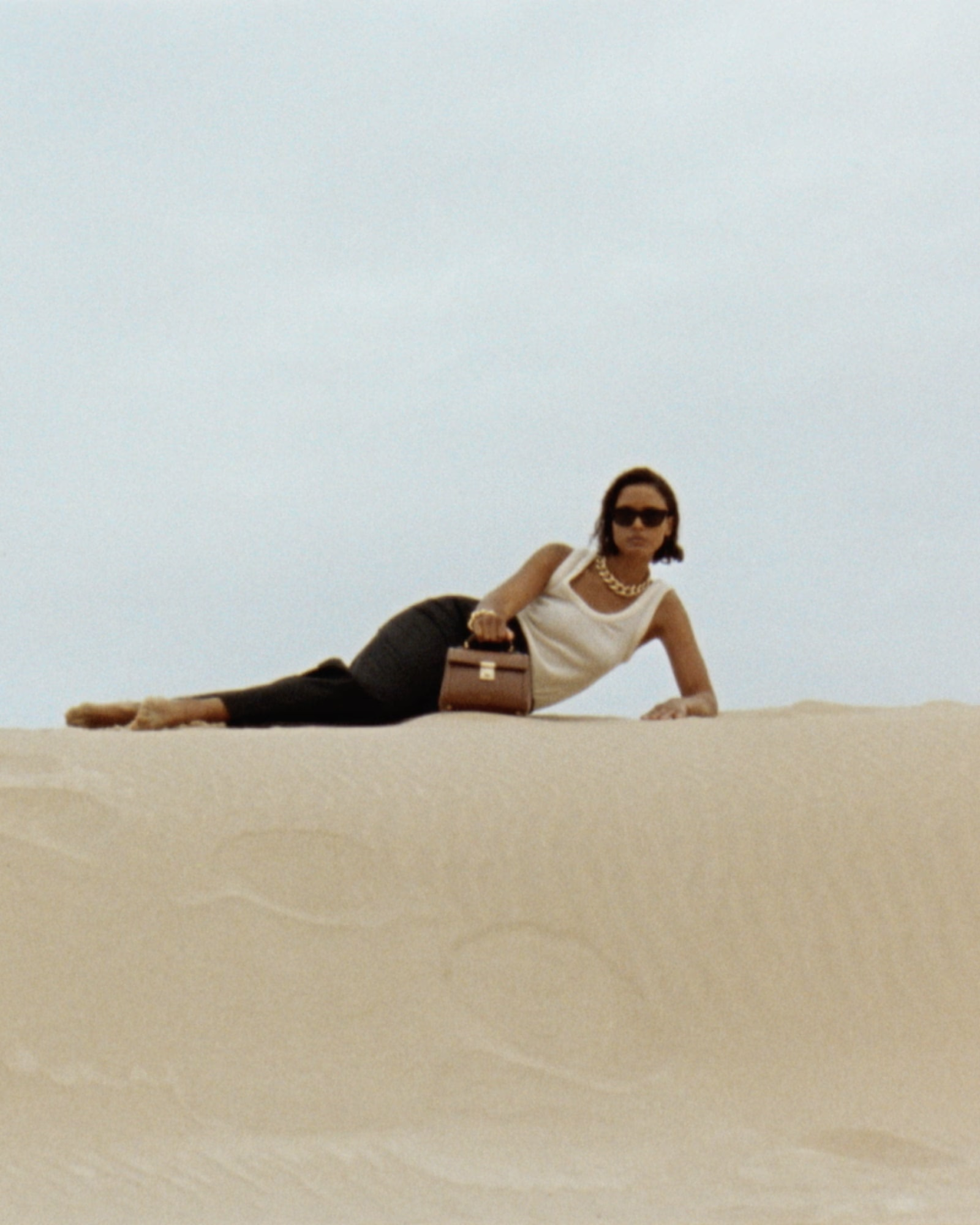 Woman reclining in a pale sand landscape